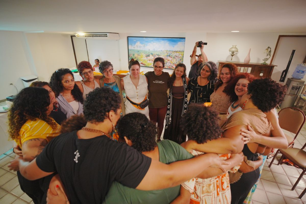 Mulheres reunidas em roda de abraço no encontro